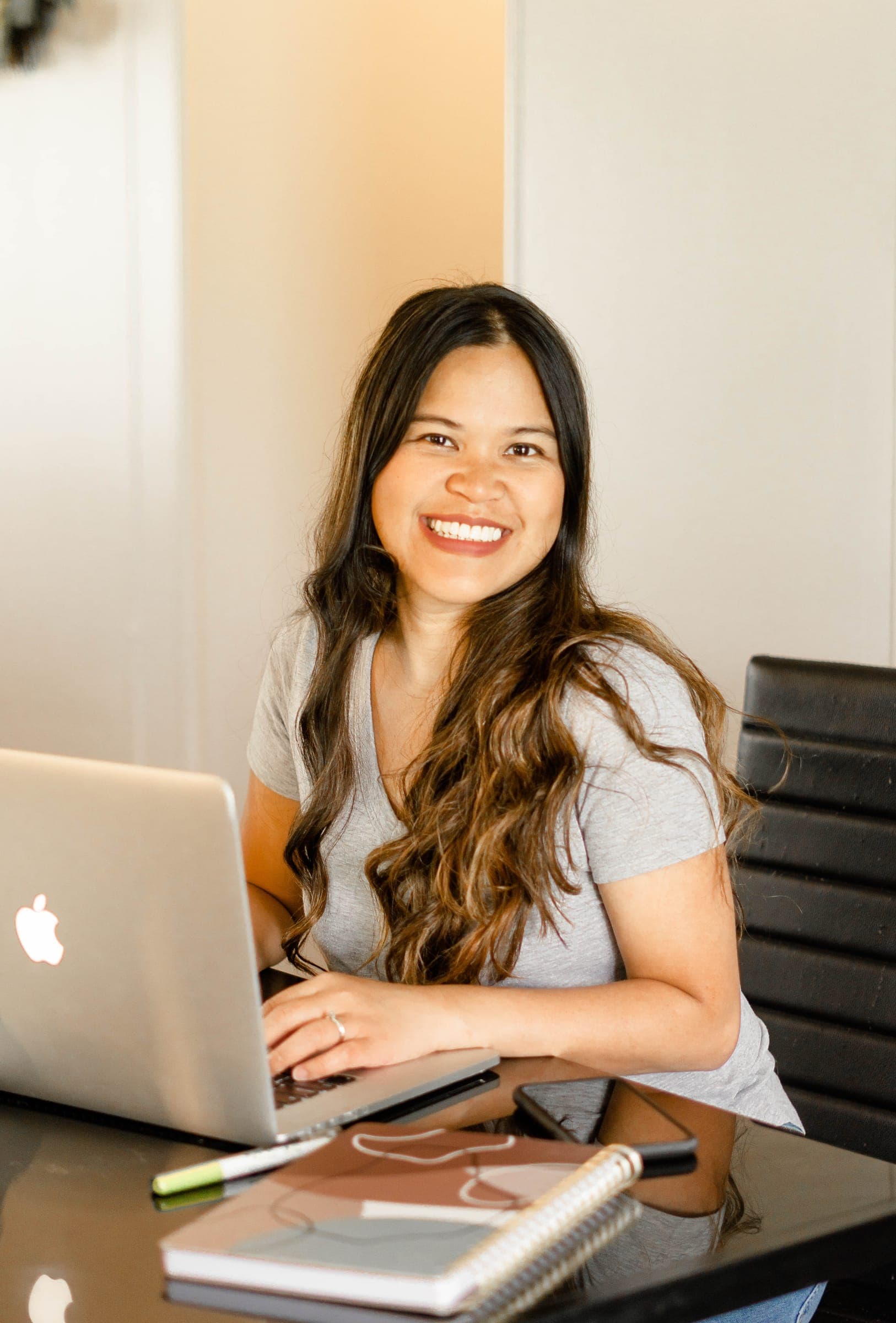 Kristy smiling at the camera while working on her laptop