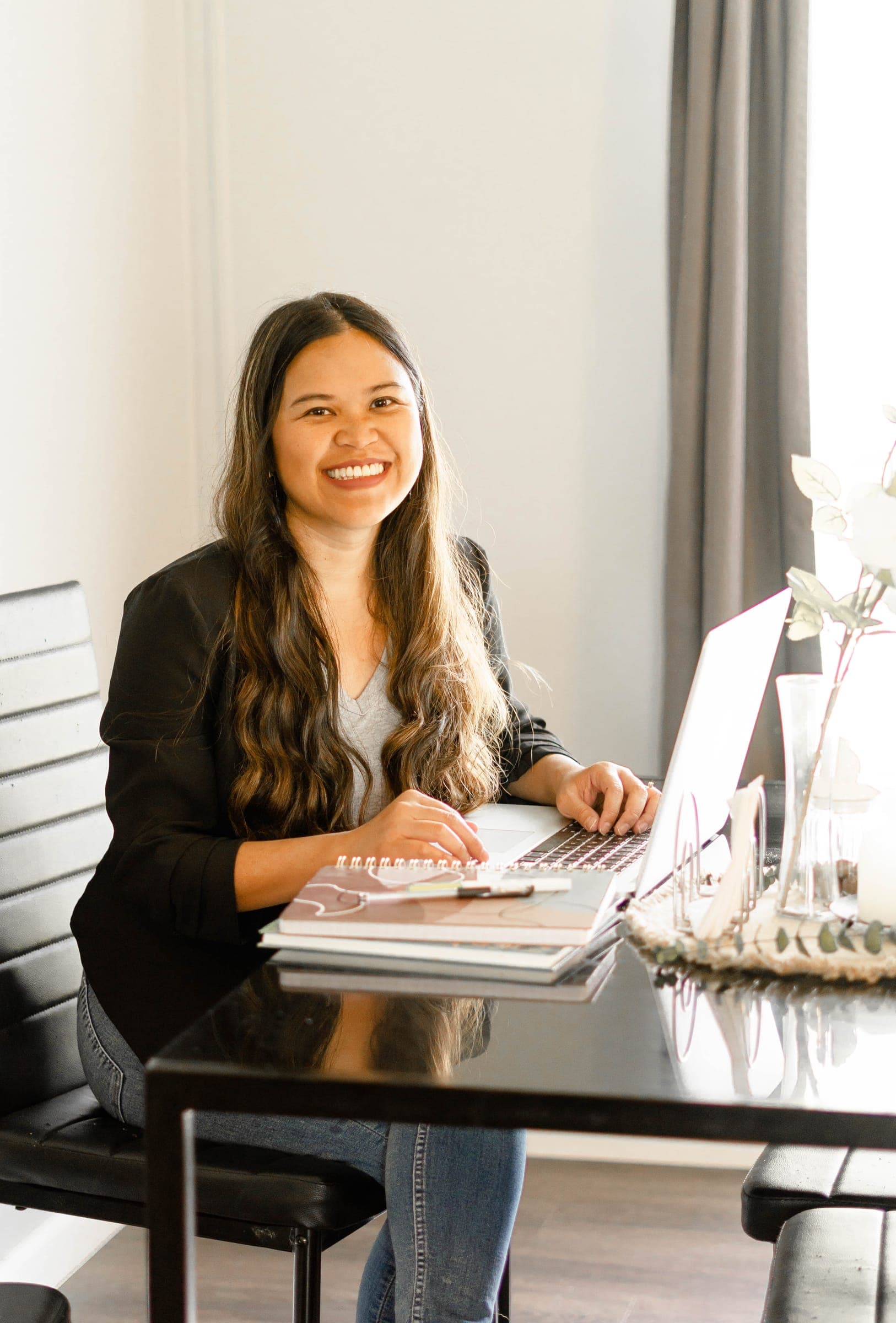 Kristy Yoder, coach for agency owners, smiling at her desk with a laptop