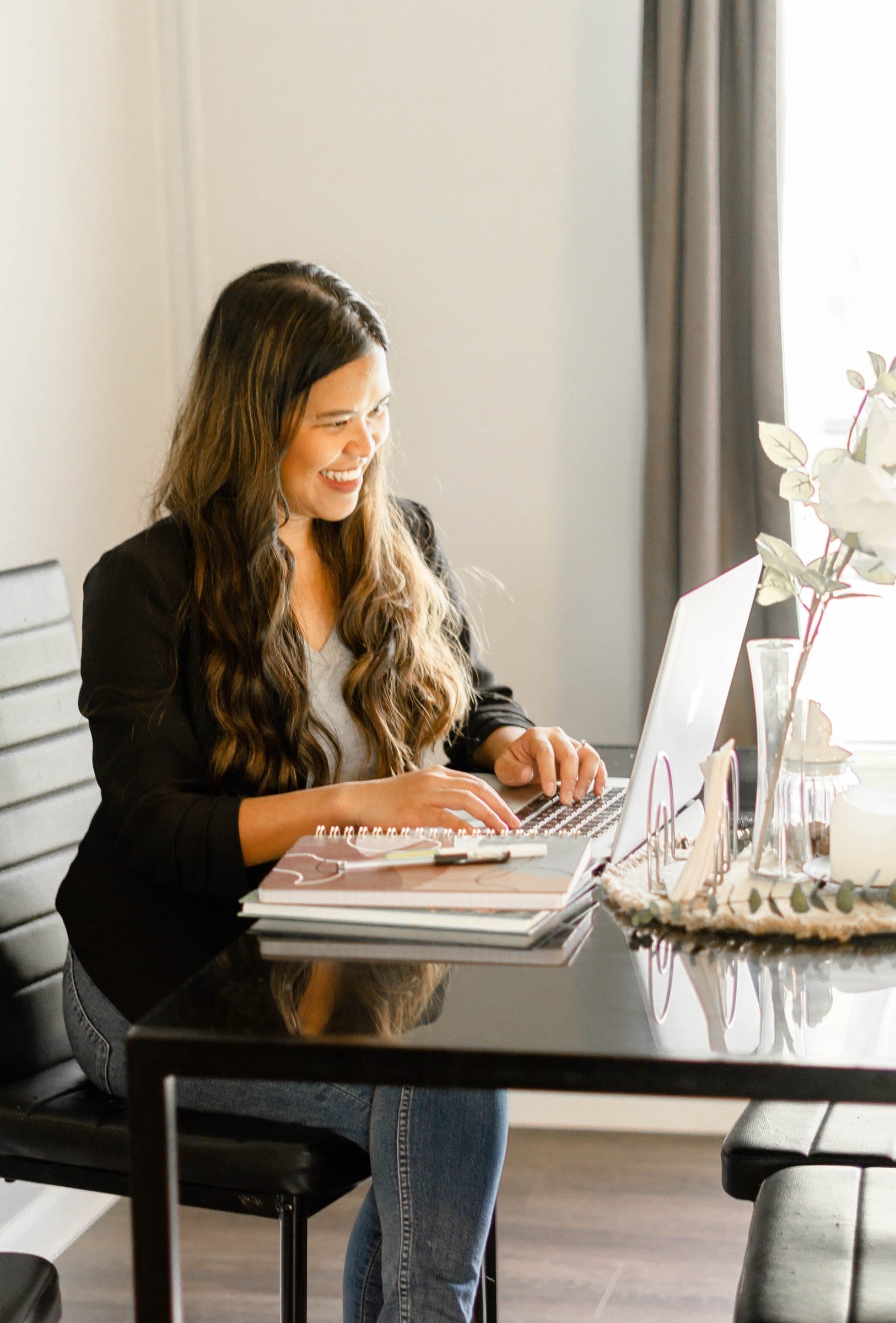 Kristy smiling while typing on her laptop at a desk