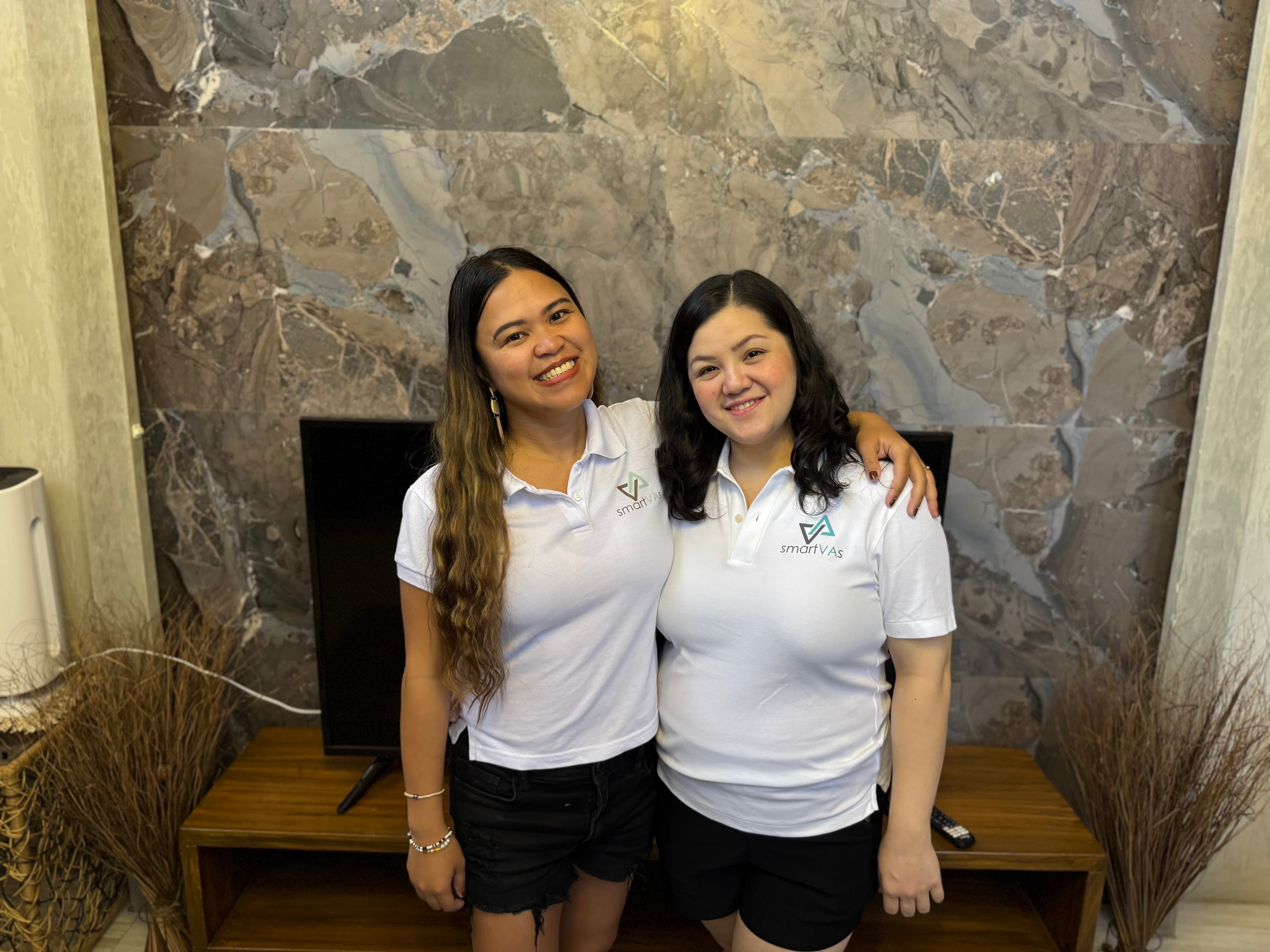 Kristy Yoder and Regine, COO of SmartVAs, smiling together in matching SmartVAs polo shirts