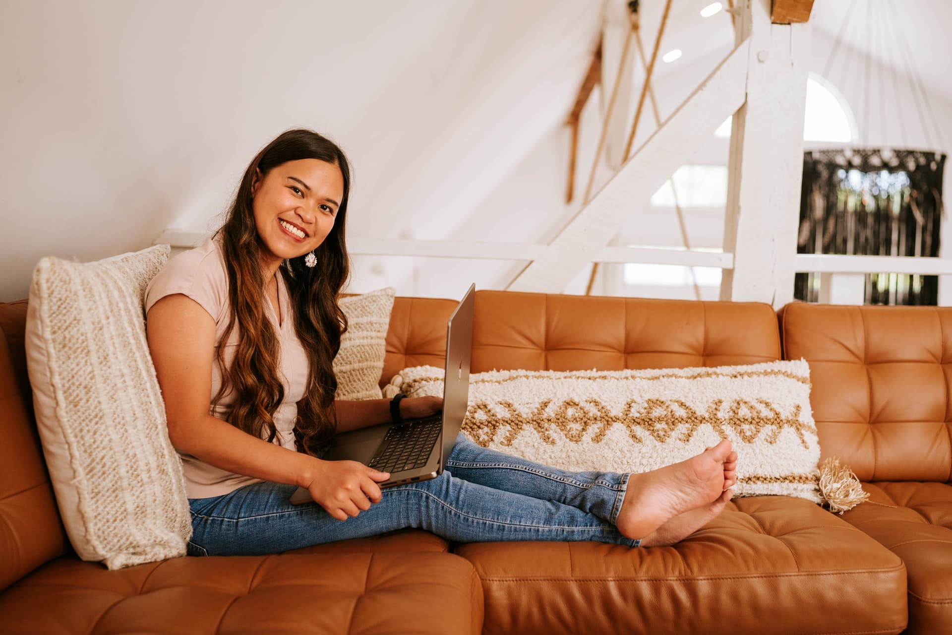 Kristy Yoder working on her laptop while relaxing on a couch